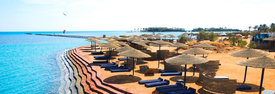 Ett tropiskt strandresort i El Gouna med solstolar och parasoller längs en azurblå kuststräcka.