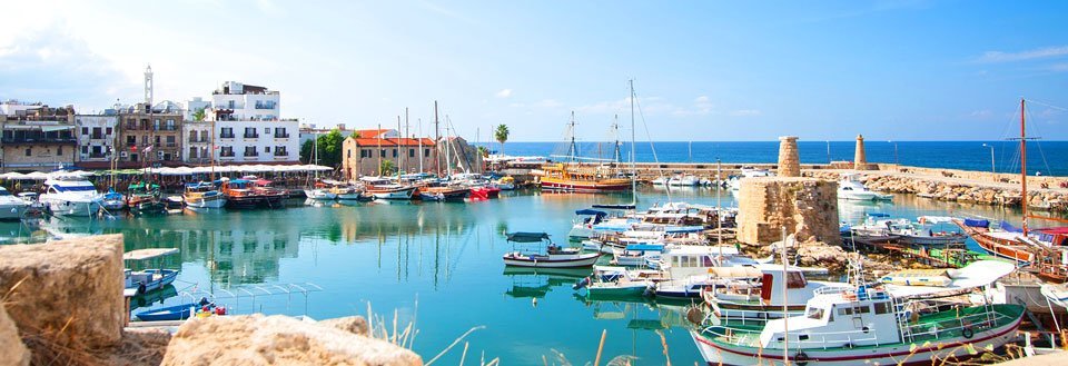 Pittoresk hamn med färgglada båtar och traditionella byggnader under en klarblå himmel.