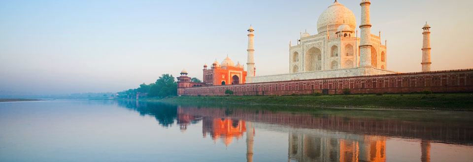 Taj Mahal vid Yamunafloden i kvällssolen, speglar sig i vattnet.