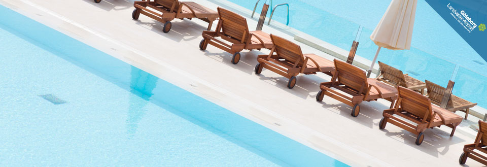 Solstolar och en vit parasoll placerade vid kanten av en inbjudande swimmingpool.