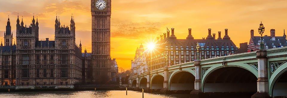 Solnedgång bakom Big Ben och Westminsterpalatset i London, med Westminster Bridge i förgrunden.