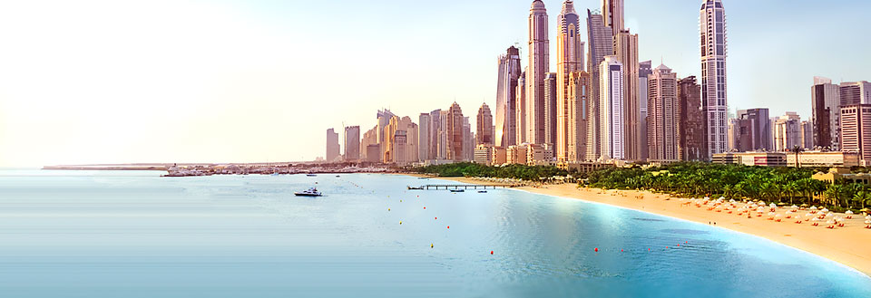 Panoramavy över en modern kuststad med skyskrapor och en sandstrand framför ett klarblått hav.
