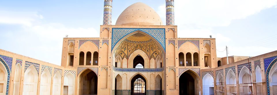 Antik moské med imponerande valv och detaljrik kakelkonst under en klarblå himmel.