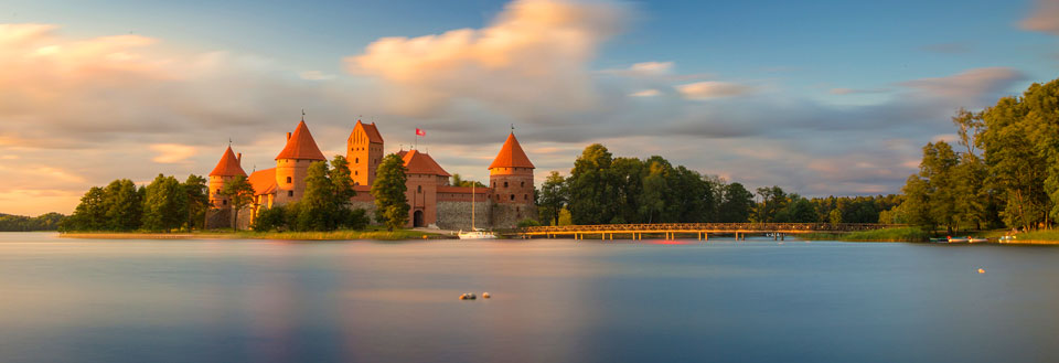 Majestätiskt medeltida slott omgivet av vatten vid solnedgången.