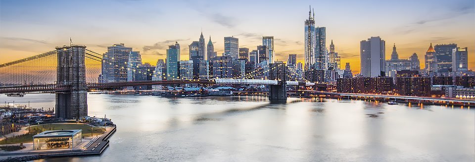 Brooklyn Bridge och Manhattan skyline i skymningen med belysta byggnader.