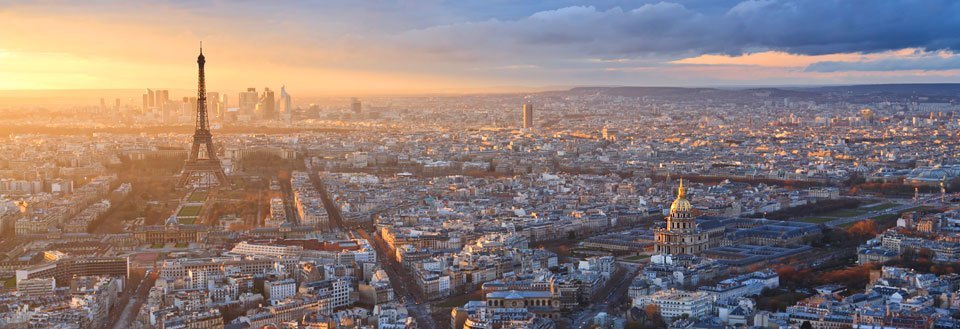 Panoramavy över Paris i solnedgången med Eiffeltornet och stadens kompakta bebyggelse.