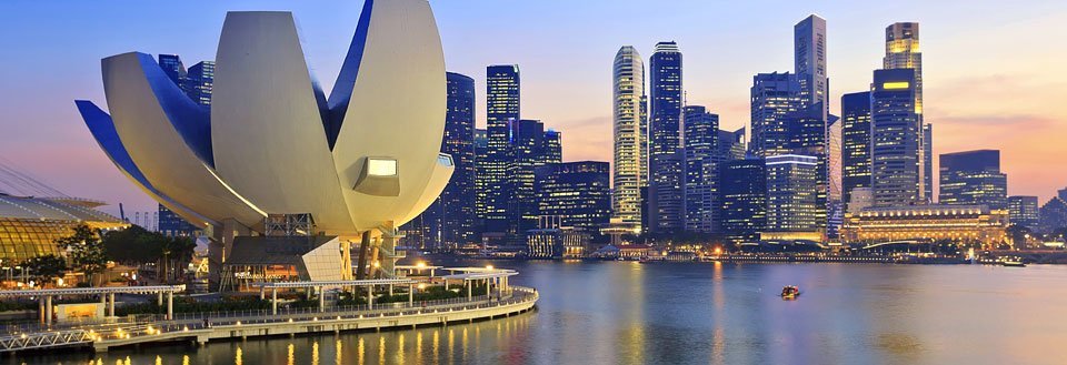 Singapores skyline vid solnedgången med ArtScience Museum i förgrunden vid marinan.