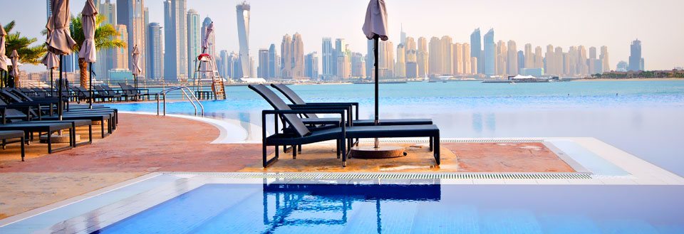 Lyxig pool framför en modern stadssilhuett med imponerande skyskrapor i Dubai.