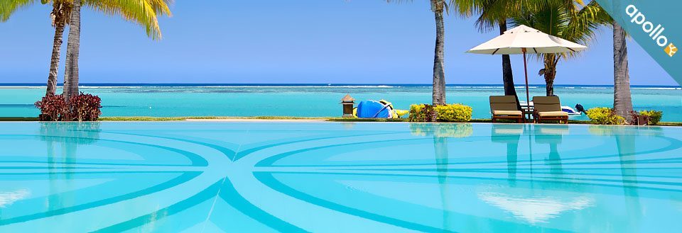 En lugn pool med kristallklart blått vatten, palmer och havet i bakgrunden.