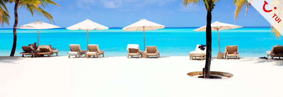 Vita sandstränder med solstolar under parasoller framför det azurblå havet.