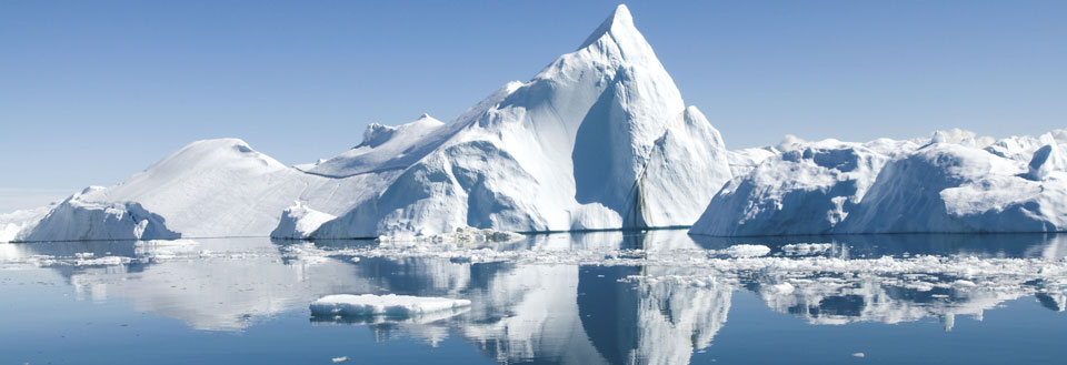 Imponerande isberg i ett lugnt polarhav med speglingar i det kristallklara vattnet.