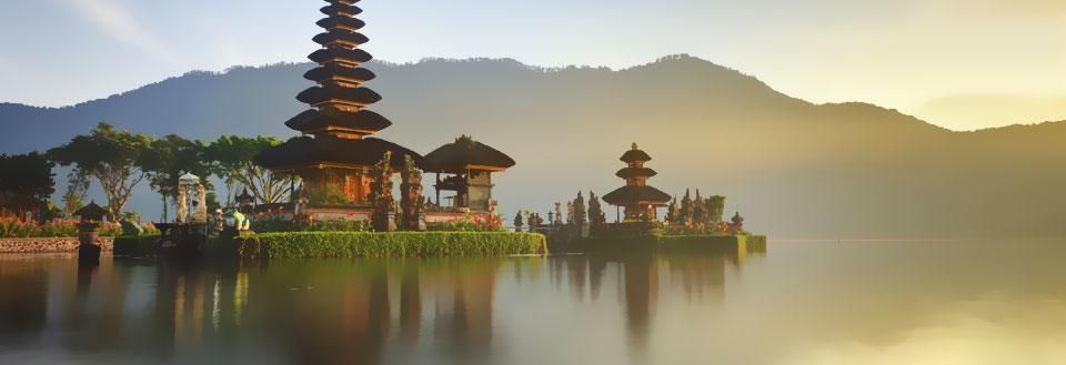 Ett fridfullt tempel vid sjökanten med berg i bakgrunden vid soluppgång.
