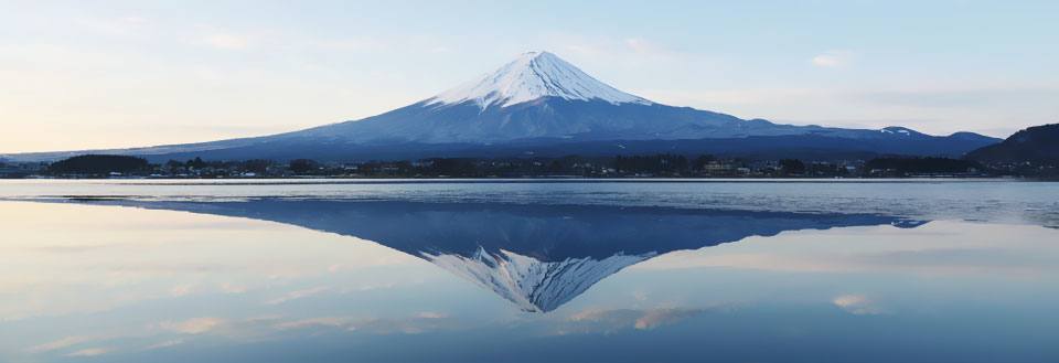 En stillsam vy av Mount Fuji som speglas exakt i en lugn sjö i skymningen.