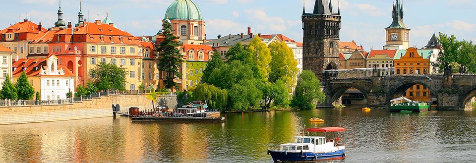 Vacker flodutsikt med en traditionell båt omgiven av historiska byggnader och en ikonisk bro.