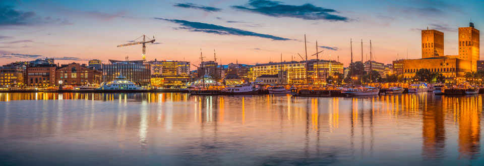 Panoramavy över Rygge i skymningen med upplysta byggnader och spegling i vattnet.